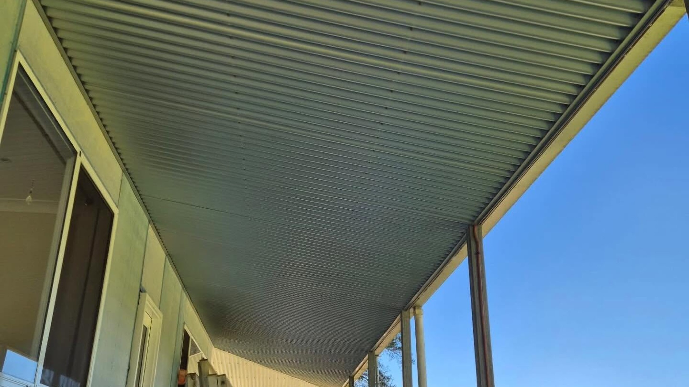 A new patio roof seen from underneath against a clear sky