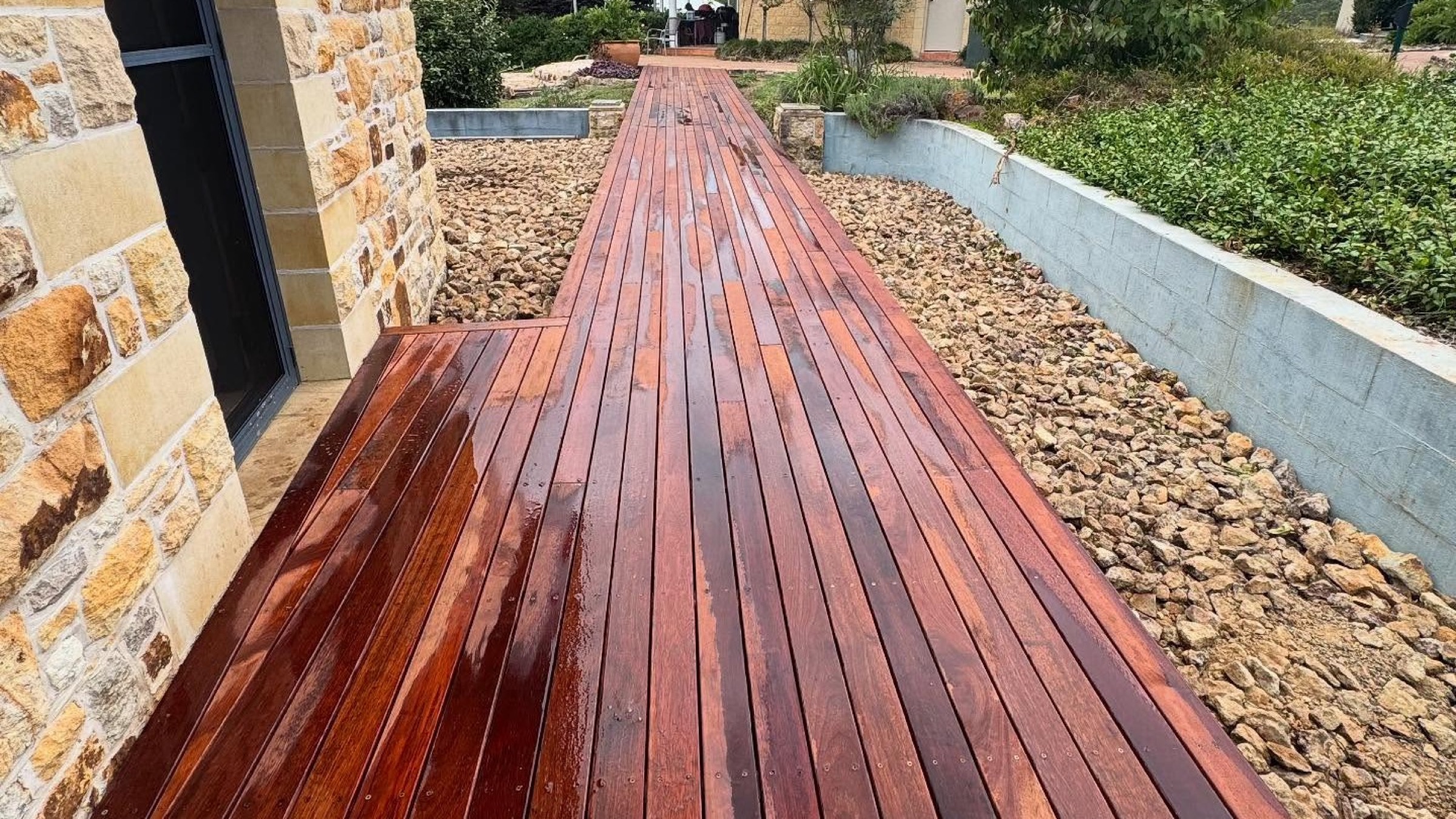A hardwood deck walkway running alongside a stone retaining wall