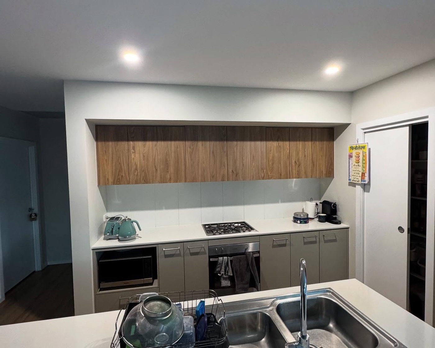 A renovated kitchen with timber overhead cabinets and a stone benchtop