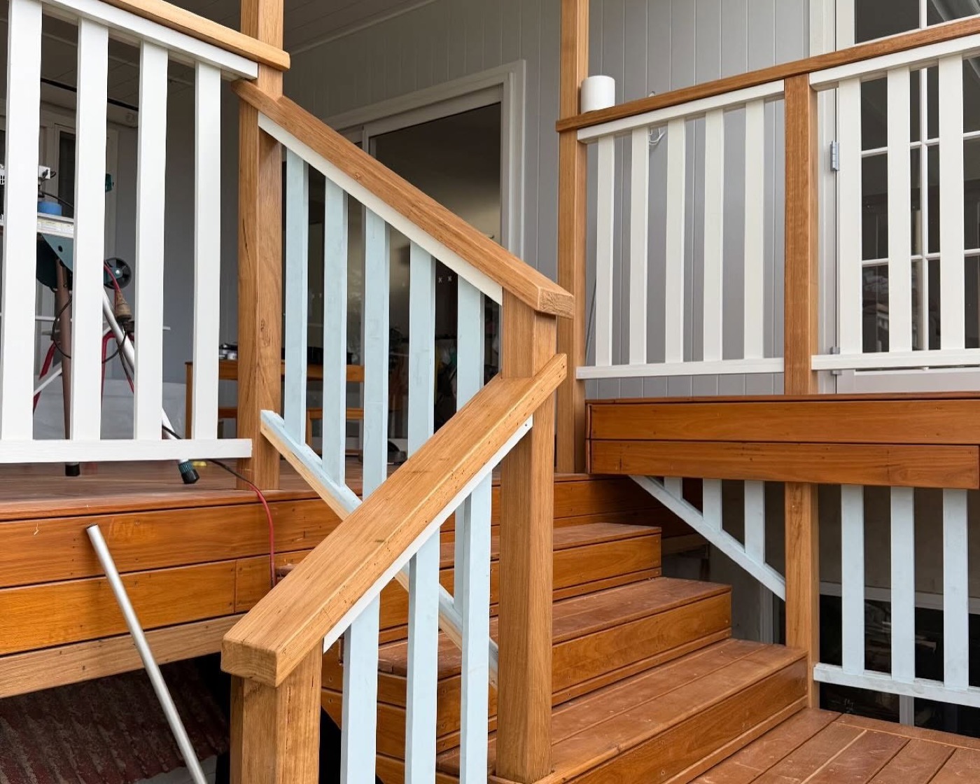 A timber staircase with a painted balustrade meeting a deck landing