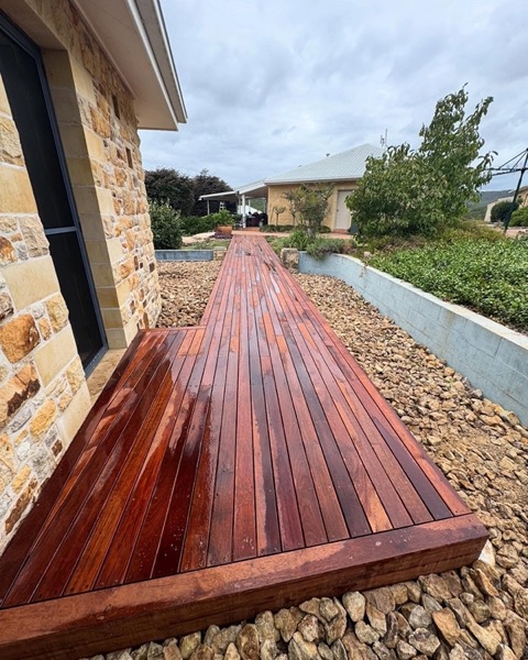 A hardwood deck walkway running beside a stone retaining wall