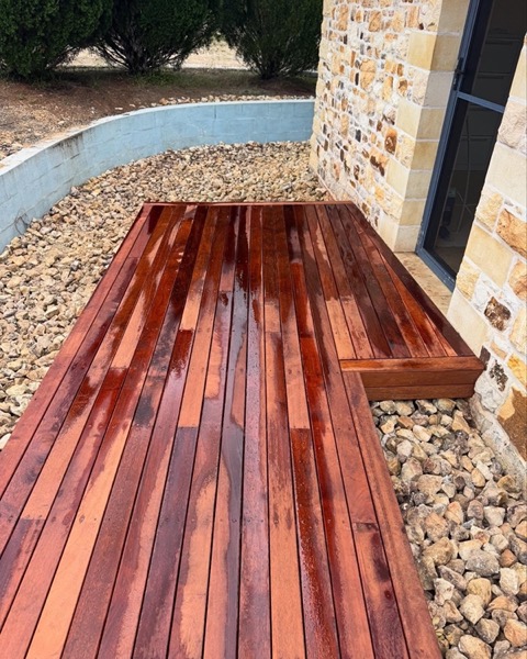 Hardwood decking laid against a stone wall over a pebble bed