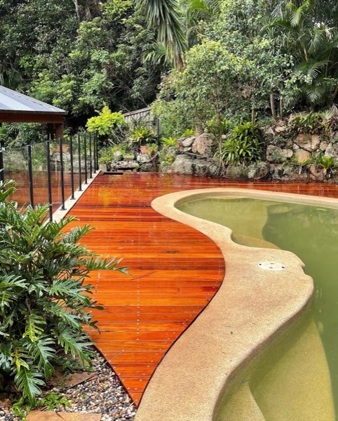 A timber deck curving around the edge of a swimming pool