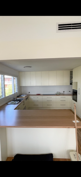 A kitchen benchtop and cabinetry over timber flooring