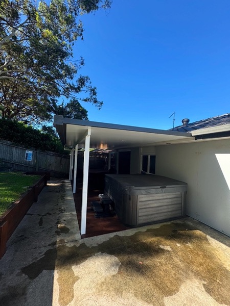 A carport area alongside the house with a spa in place