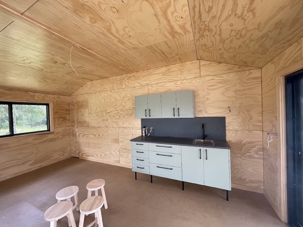 A plywood lined room with a kitchenette installed